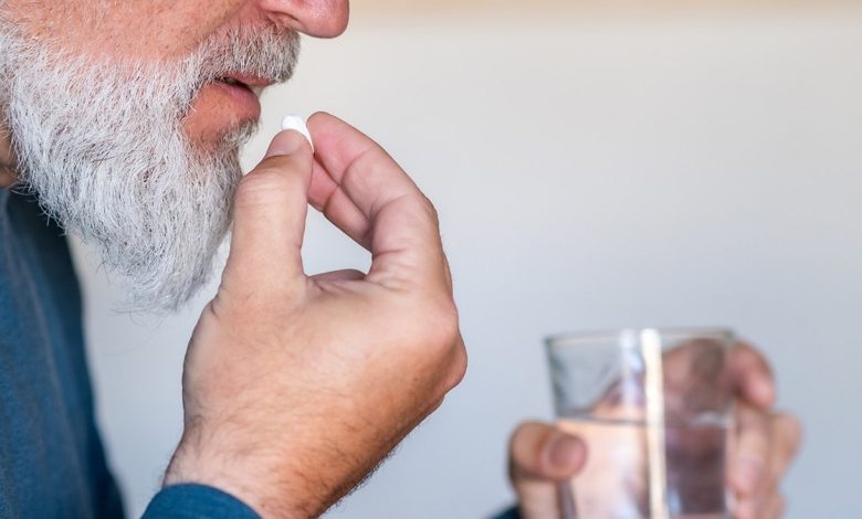 man puts pill in mouth