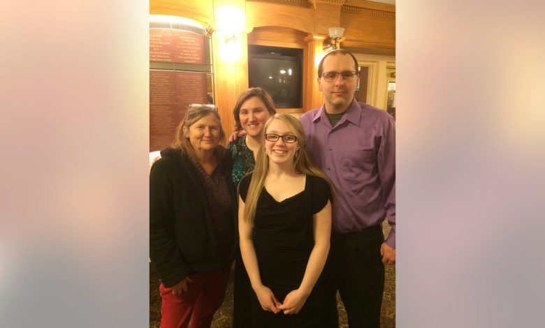 Emily Ferlazzo wearing a black dress and smiling with her family.