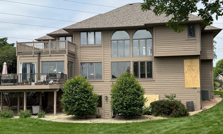 rear side of large beige house with some windows boarded up