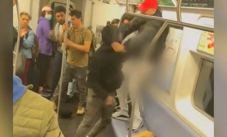 man in black hoody attacks another man in crowded train car