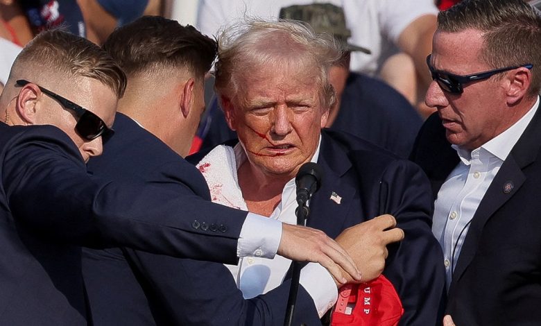 Donald Trump gestures with a bloodied face as multiple shots rang out during a campaign rally