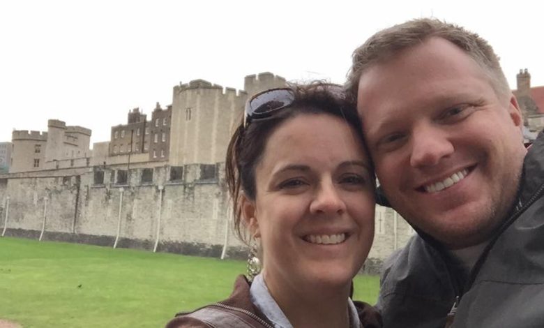 Angela and James Craig pose for selfie with green lawn and gray castle in background