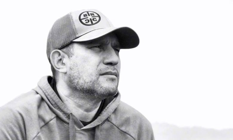 Dan Rivera in a hoodie and hat, looking into the distance
