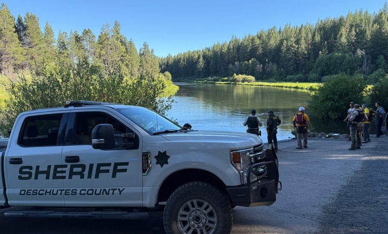 sheriff's vehicle and searchers on riverbank