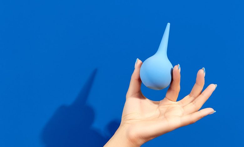 Woman's hand holding an enema device