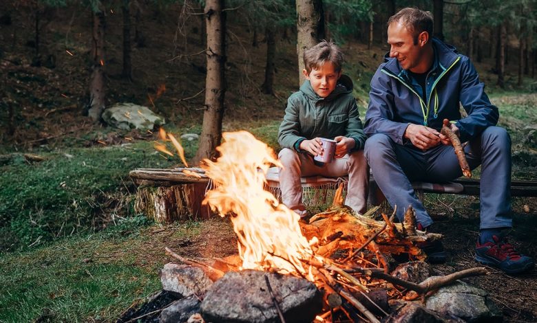 father and son sit near a campfire