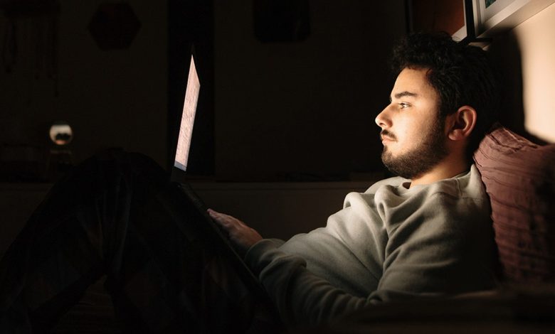 A young man in bed using his laptop
