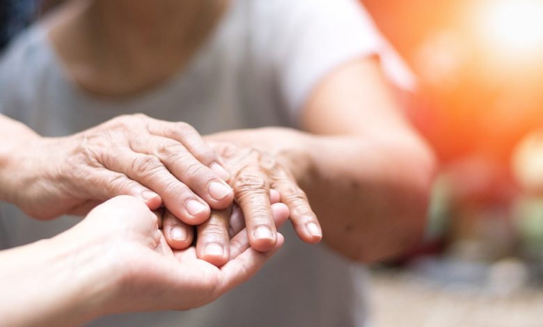 Doctor's hand holding the hand of someone with Parkinson's