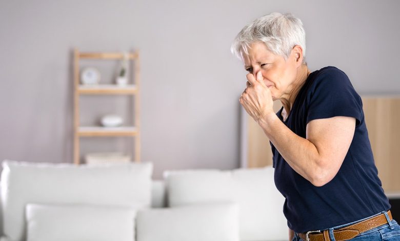 Woman holding nose due to smell.