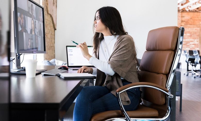 woman sits at desk in office on video call